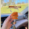 Close-up of car hanging ornament with dried orange slices, ribbon bow, and bell