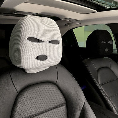 Knitted car headrest covers in black and white, with eye-shaped cutout design, shown installed on car seats