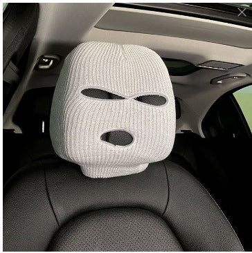 White knitted car headrest cover with eye-shaped cutout design, installed on a car seat in the interior
