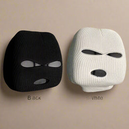 Set of black and white knitted car pillow covers with eye-shaped design, displayed on a beige background