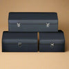 Set of three dark blue leather car trunk storage boxes in different sizes on a beige background