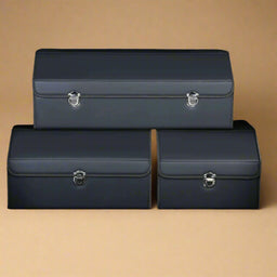 Set of three dark blue leather car trunk storage boxes in different sizes on a beige background